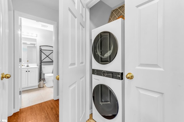 laundry area with stacked washer and dryer, laundry area, and light wood-style floors