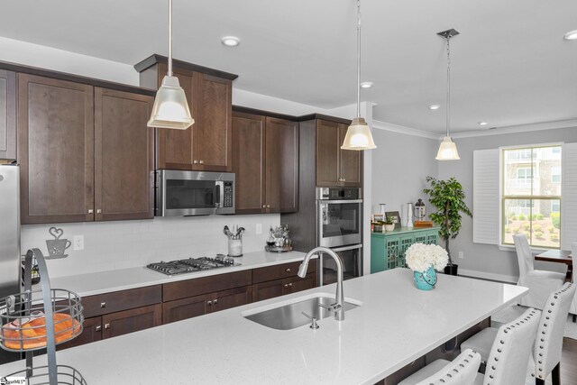 kitchen featuring stainless steel appliances, a sink, dark brown cabinets, decorative backsplash, and a breakfast bar