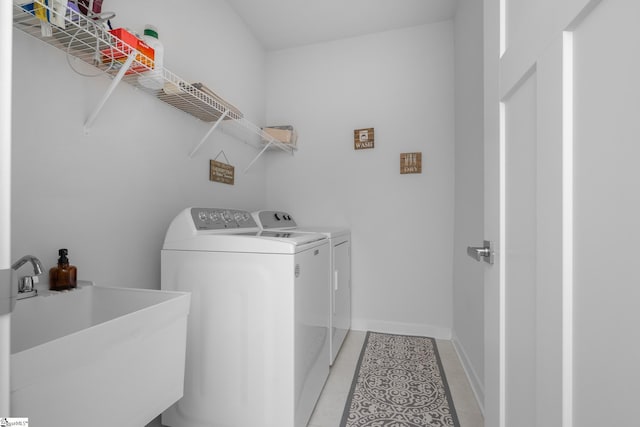 laundry room with a sink, light tile patterned floors, washer and dryer, baseboards, and laundry area