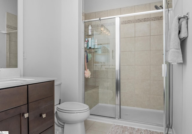 bathroom featuring toilet, vanity, tile patterned flooring, and a stall shower