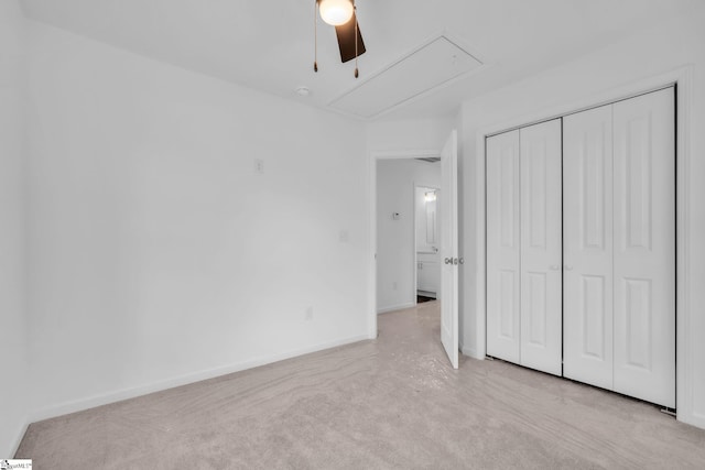 unfurnished bedroom featuring attic access, baseboards, a closet, and light colored carpet