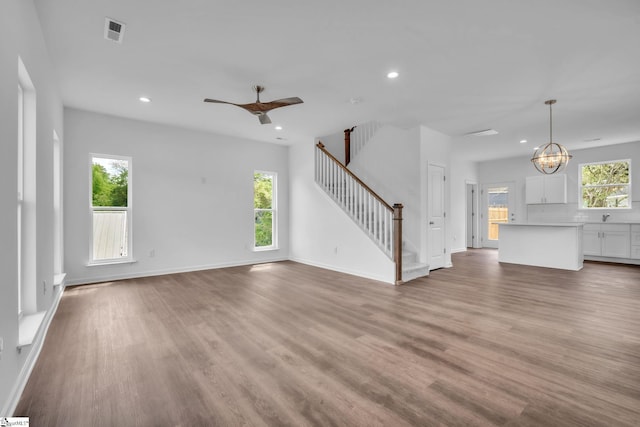 unfurnished living room with wood finished floors, visible vents, recessed lighting, and stairway