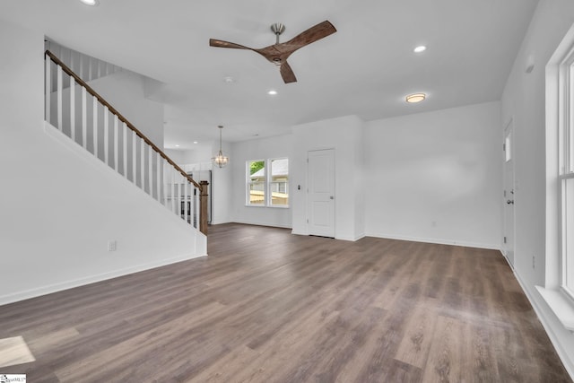 unfurnished living room with recessed lighting, stairs, and ceiling fan with notable chandelier