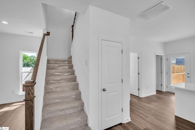 stairway featuring baseboards, wood finished floors, visible vents, and recessed lighting