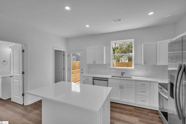 kitchen with dark wood finished floors, backsplash, visible vents, a sink, and appliances with stainless steel finishes