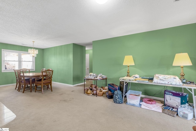 recreation room with carpet, a textured ceiling, baseboards, and a notable chandelier