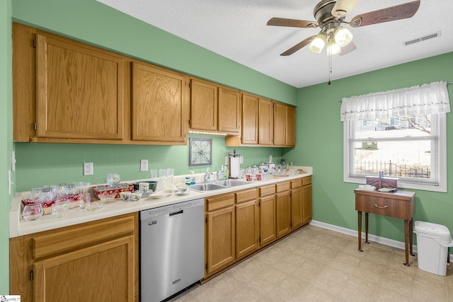 kitchen with light countertops, visible vents, stainless steel dishwasher, a sink, and baseboards