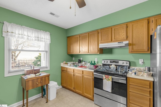 kitchen featuring visible vents, a ceiling fan, light countertops, under cabinet range hood, and appliances with stainless steel finishes