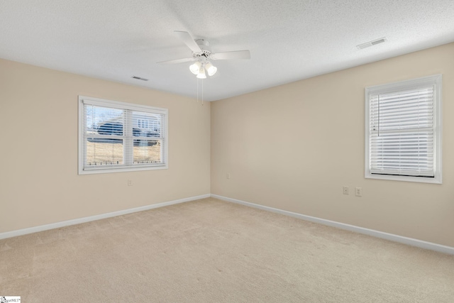 empty room with light colored carpet, ceiling fan, baseboards, and visible vents
