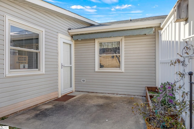 doorway to property featuring roof with shingles and a patio area