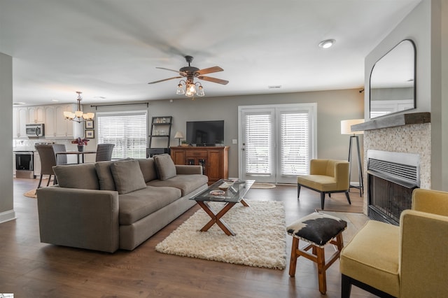 living room featuring a fireplace, wood finished floors, a wealth of natural light, and ceiling fan with notable chandelier