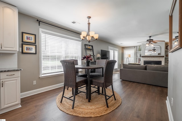 dining room with dark wood-style floors, baseboards, visible vents, and ceiling fan with notable chandelier