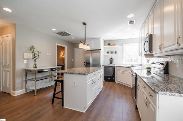 kitchen with stainless steel appliances, open shelves, visible vents, a sink, and a center island