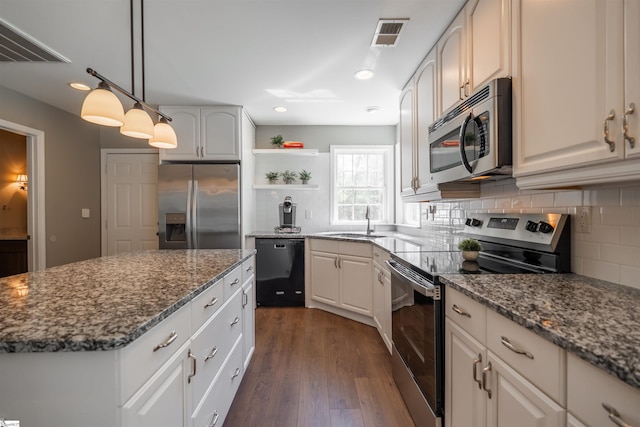 kitchen with dark stone countertops, open shelves, backsplash, visible vents, and appliances with stainless steel finishes