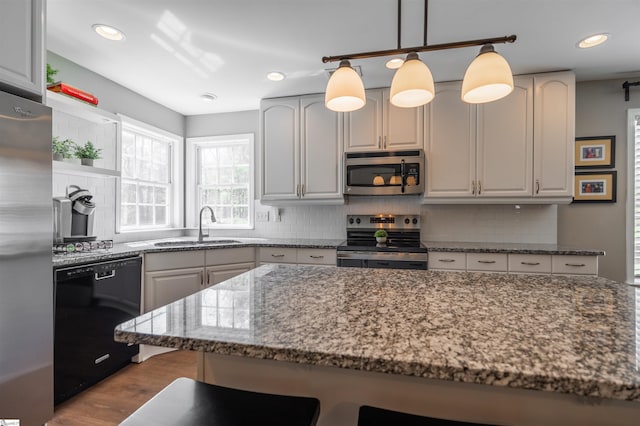 kitchen featuring backsplash, dark stone countertops, appliances with stainless steel finishes, and a sink
