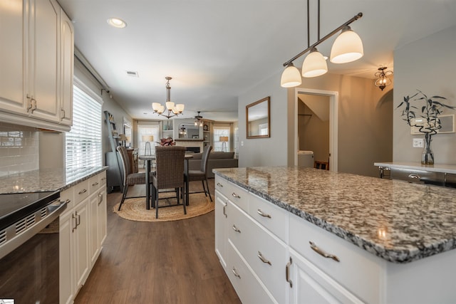 kitchen featuring white cabinets, range with electric cooktop, a chandelier, stone countertops, and dark wood-type flooring