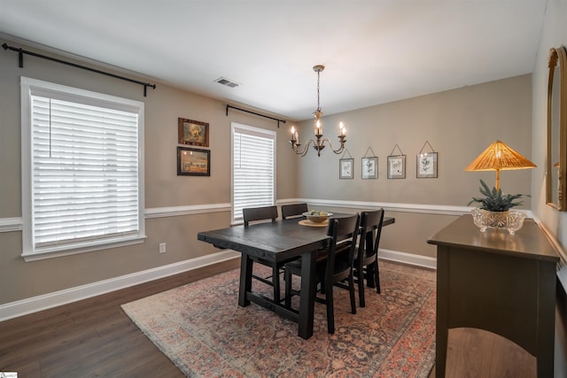 dining area with baseboards, visible vents, a notable chandelier, and dark wood-style flooring