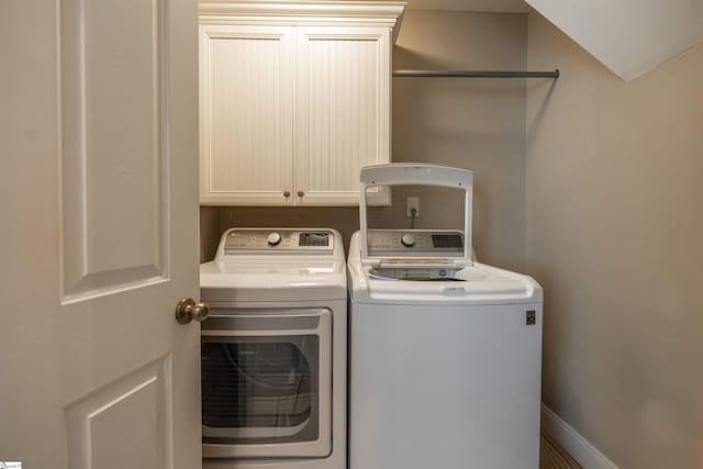 laundry room featuring washing machine and dryer, baseboards, and cabinet space