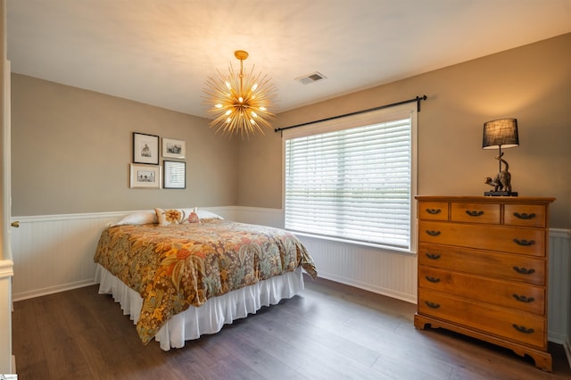 bedroom with a chandelier, dark wood finished floors, visible vents, and wainscoting