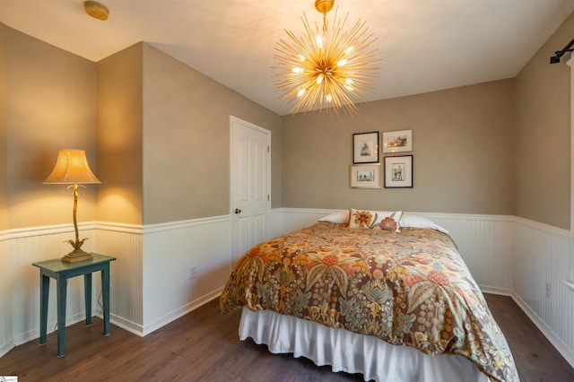 bedroom with wood finished floors, a wainscoted wall, and a notable chandelier