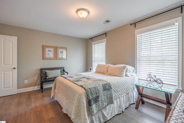bedroom featuring baseboards, wood finished floors, and visible vents