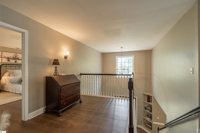 hall featuring baseboards, dark wood-style flooring, and an upstairs landing