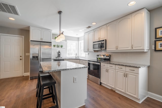 kitchen featuring light stone countertops, visible vents, appliances with stainless steel finishes, and a sink