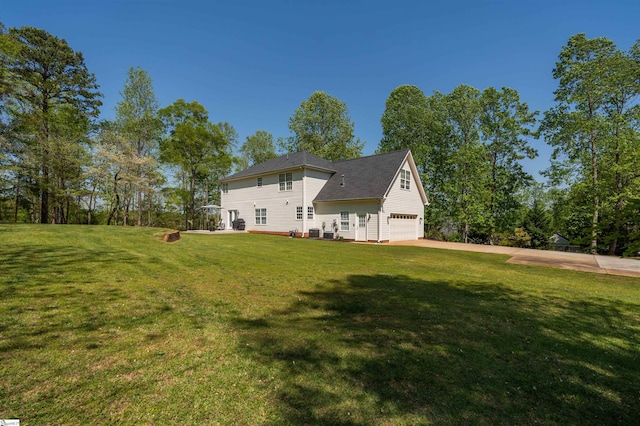 back of property featuring concrete driveway, an attached garage, and a yard
