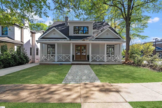 view of front of property with a porch, a shingled roof, and a front yard
