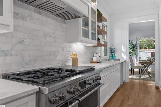kitchen with high end range, glass insert cabinets, custom range hood, backsplash, and white cabinetry
