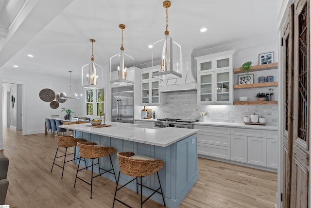kitchen with built in refrigerator, open shelves, decorative backsplash, range, and a kitchen island