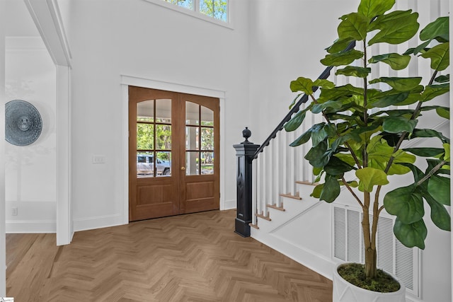 entrance foyer featuring baseboards, a high ceiling, stairs, and french doors