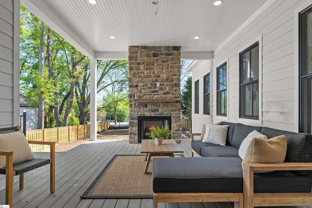 deck with an outdoor living space with a fireplace and fence