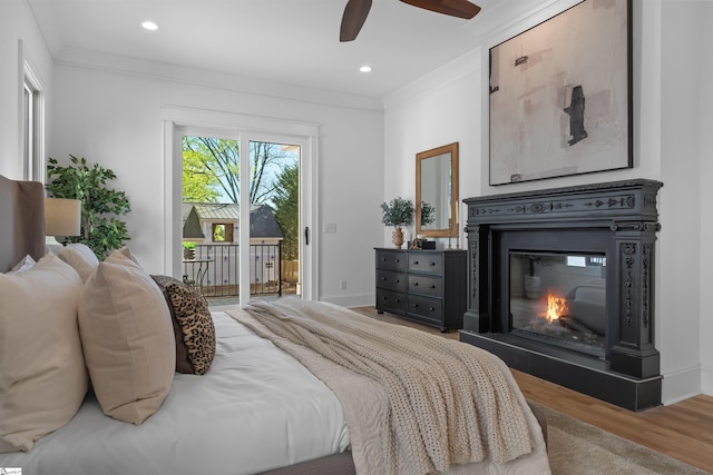 bedroom featuring recessed lighting, wood finished floors, access to exterior, crown molding, and a glass covered fireplace