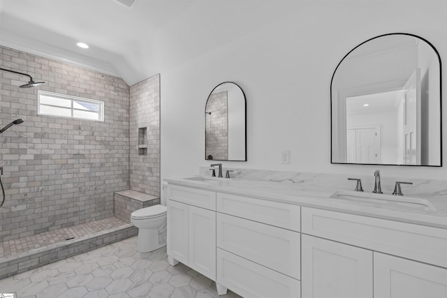 bathroom featuring a tile shower, tile patterned floors, double vanity, toilet, and a sink