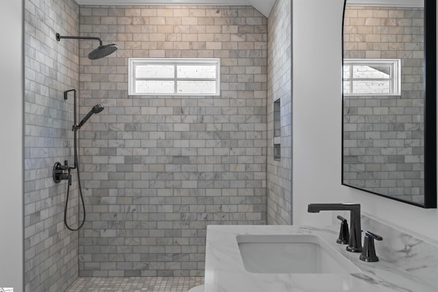 full bathroom with a tile shower and a sink