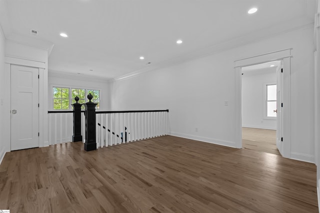 spare room with baseboards, crown molding, wood finished floors, and recessed lighting
