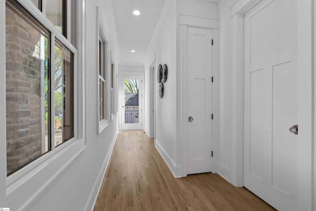 hall featuring baseboards, crown molding, light wood-style floors, and recessed lighting