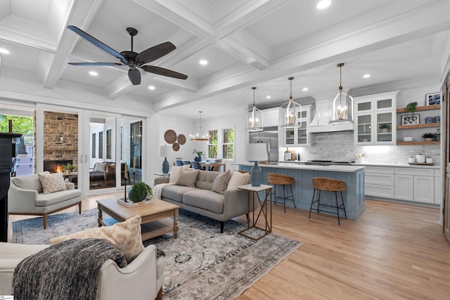 living room featuring light wood-type flooring, recessed lighting, coffered ceiling, a ceiling fan, and a warm lit fireplace