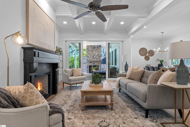 living area with coffered ceiling, beam ceiling, a large fireplace, and ceiling fan with notable chandelier