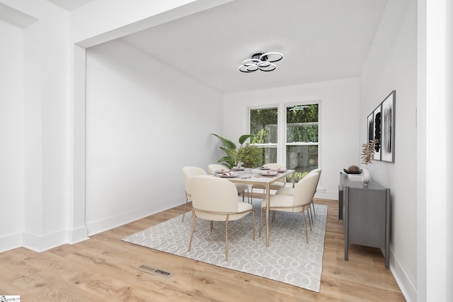 dining area with baseboards, light wood-style floors, and visible vents