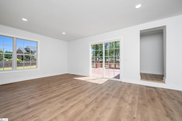 spare room with wood finished floors, visible vents, and baseboards