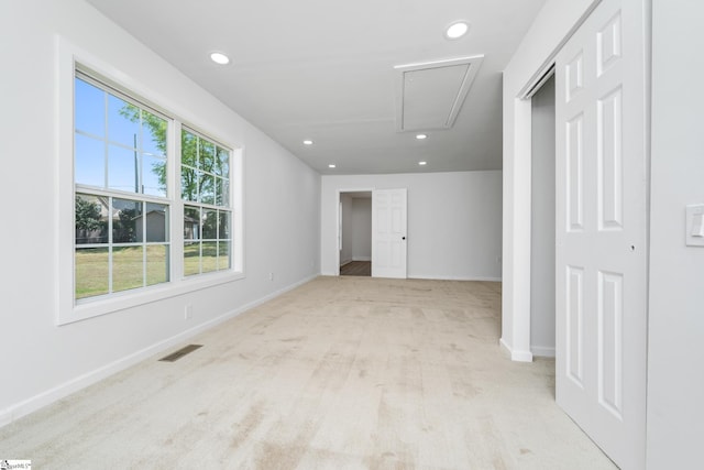 empty room featuring recessed lighting, visible vents, light carpet, baseboards, and attic access