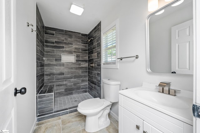 full bath featuring toilet, vanity, a tile shower, baseboards, and tile patterned flooring