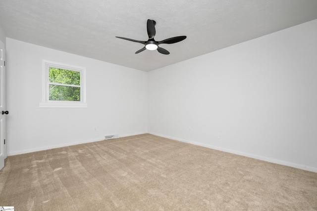 empty room with visible vents, a ceiling fan, baseboards, and light carpet