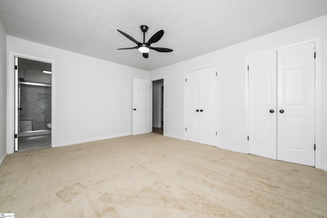 unfurnished bedroom with two closets, baseboards, connected bathroom, and carpet