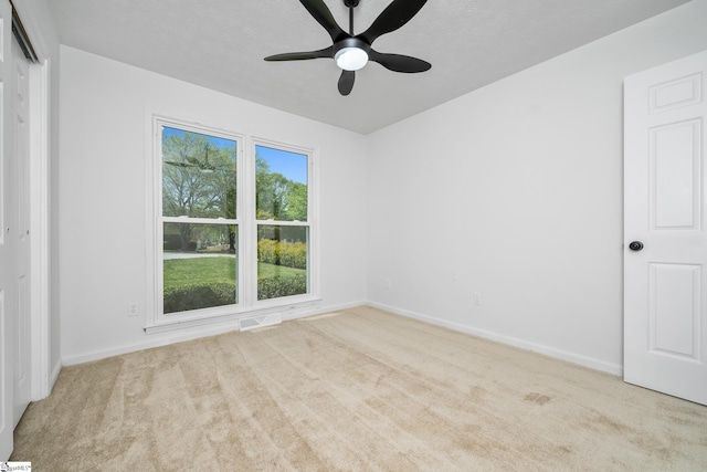 carpeted empty room featuring a ceiling fan and baseboards