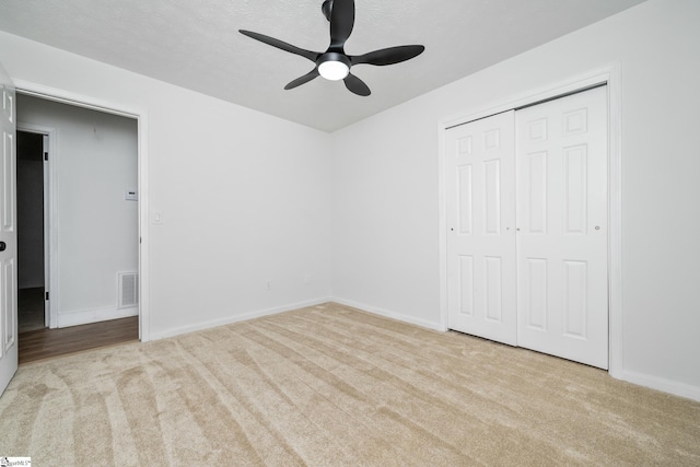 unfurnished bedroom featuring carpet, visible vents, a ceiling fan, a closet, and baseboards