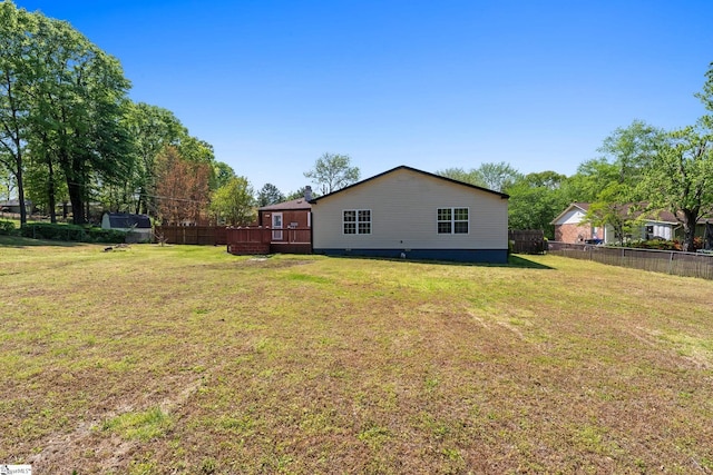 back of property with fence, a yard, and a deck
