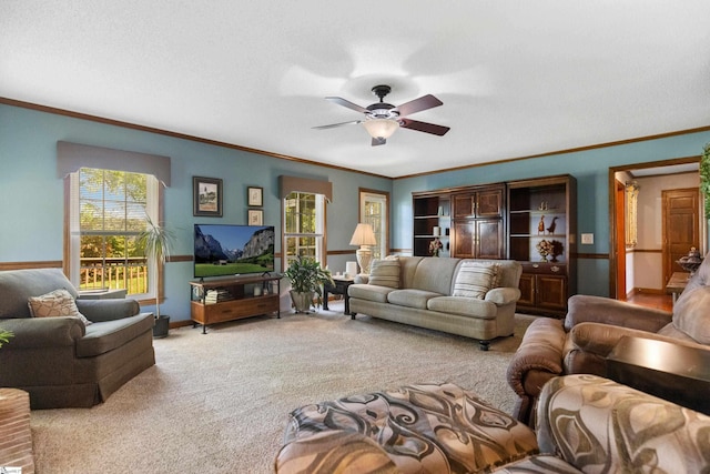 living room featuring baseboards, a ceiling fan, crown molding, and carpet